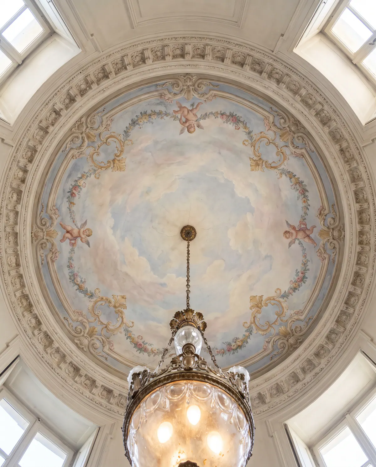 Un plafond à fresque avec ciel peint et guirlandes, un lustre de Murano.