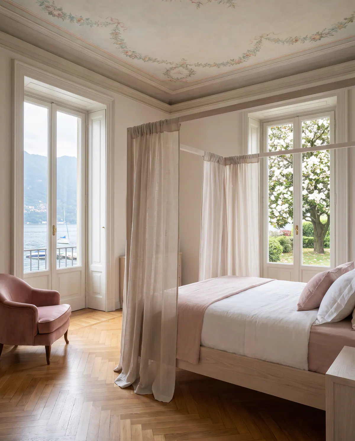 Suite Magnolia : lit à baldaquin aux voilages légers, un magnolia en fleurs derrière la fenêtre.